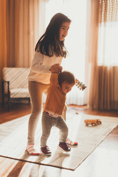 Девушка помогает младшей сестре ходить
