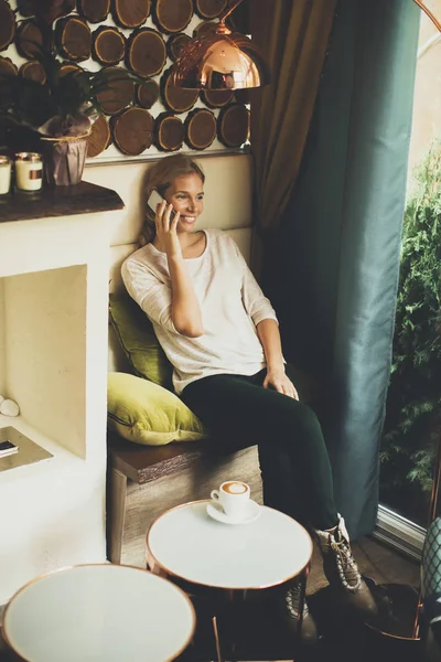 Femme assise dans un café avec téléphone — Photo