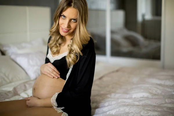 Νεαρή έγκυο γυναίκα στο κρεβάτι — Φωτογραφία Αρχείου