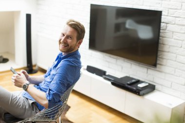 Evde cep telefonu kullanan adam.