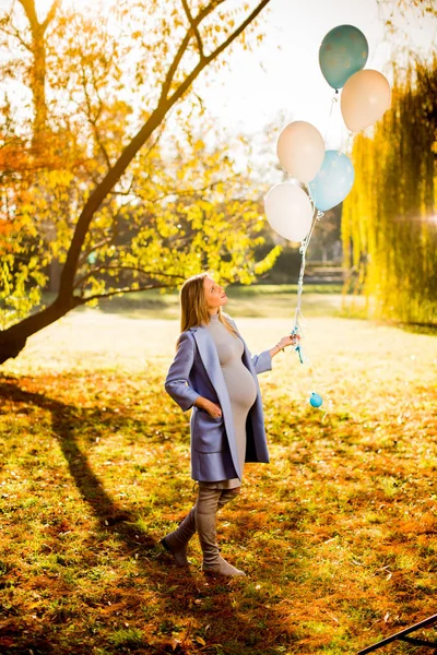 Pregnant woman with balloons in autumn forest — Stock Photo, Image