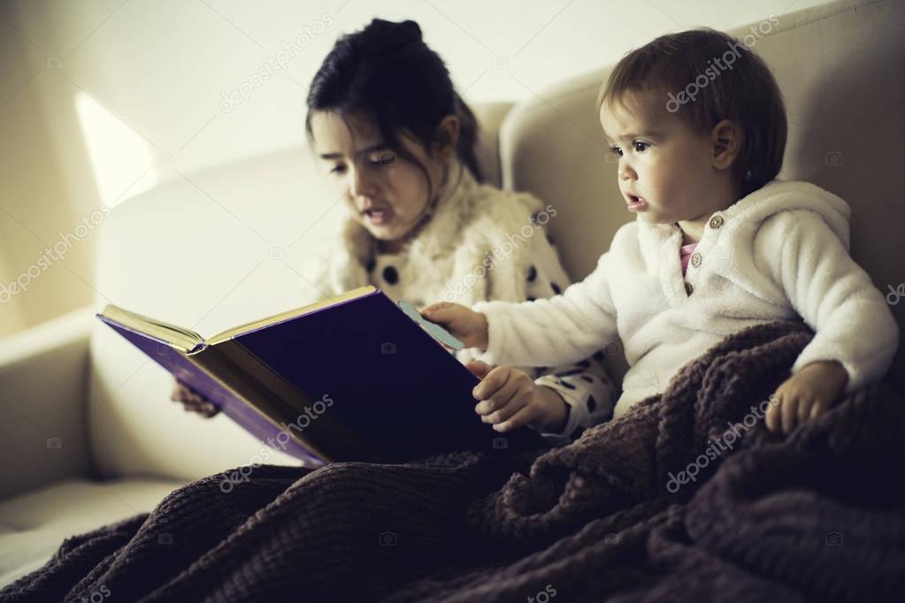 Cute little sisters reading a book