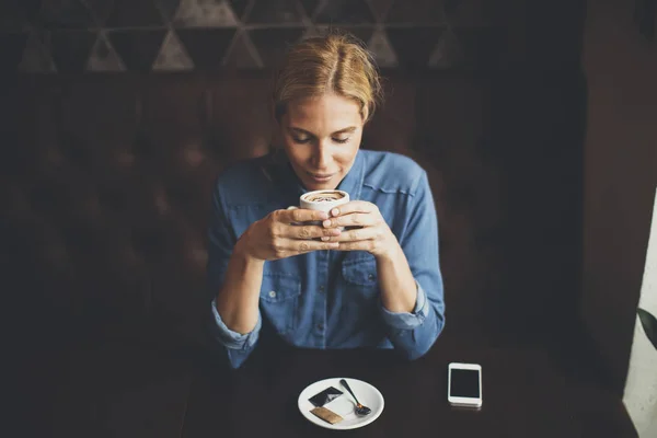 Kvinna sitter i café med telefon — Stockfoto