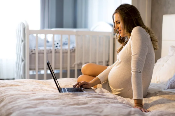 Pregnant woman with laptop in the bed — Stock Photo, Image