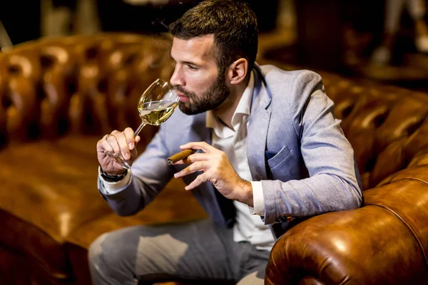 Uomo degustazione di vino e sigari affumicanti — Foto Stock