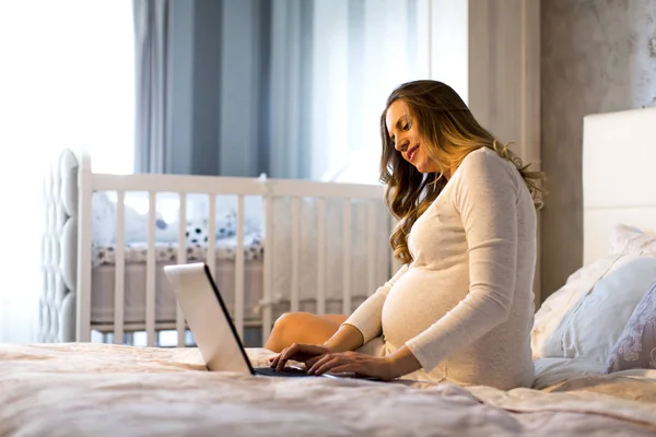 Kobieta w ciąży z laptopa w łóżku — Zdjęcie stockowe