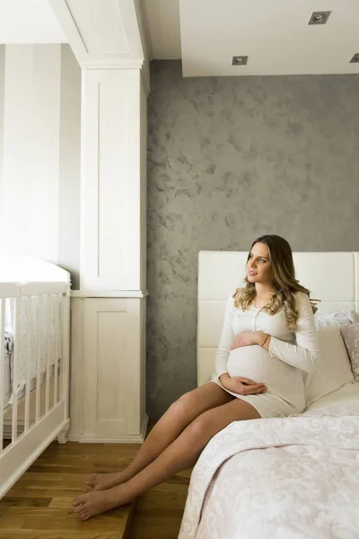Молода вагітна жінка в спальні — стокове фото