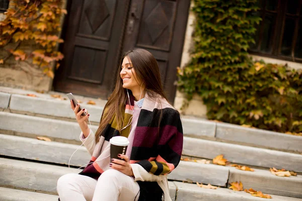 Kvinna med telefon och kaffe utomhus — Stockfoto