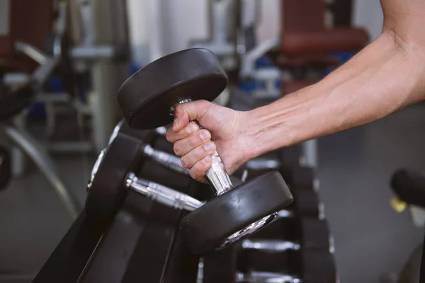 Man neemt een halter uit set — Stockfoto