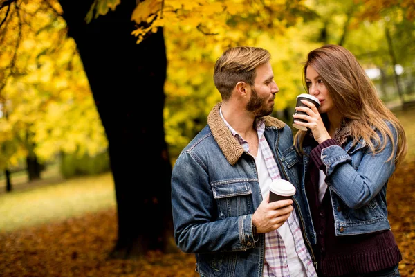 Νεαρό ζευγάρι στο Φθινοπωρινό πάρκο με καφέ — Φωτογραφία Αρχείου
