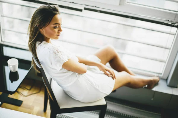 Junge Frau sitzt und träumt auf einem Stuhl — Stockfoto