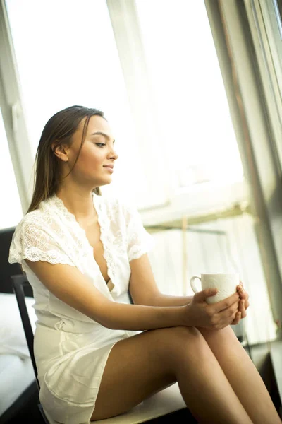 Jeune femme buvant du café en chemise de nuit — Photo