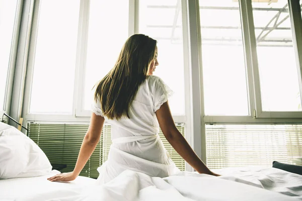 Jonge vrouw zit op een bed — Stockfoto