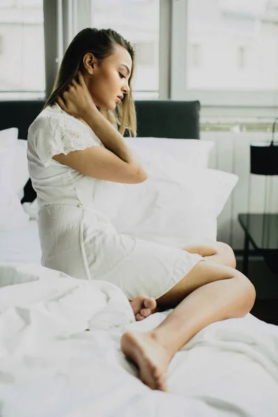 Jonge vrouw zit op een bed — Stockfoto