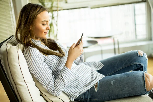 Vrolijke jonge vrouw kijken op mobiel — Stockfoto