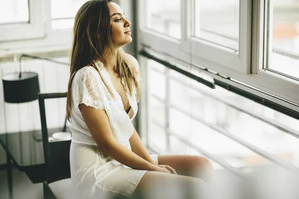 Молодая женщина сидит у окна — стоковое фото