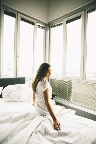 Young woman sits on a bed — Stock Photo, Image