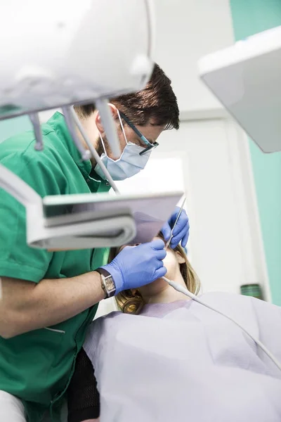 Jovencita examinándose los dientes por un dentista en el dentista —  Fotos de Stock