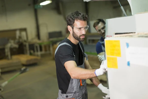 Stilig ung man som arbetar i möbelfabriken — Stockfoto