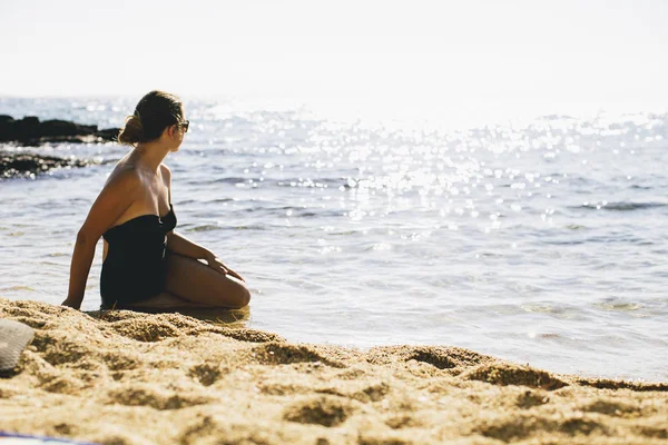 Jovens mulheres de fato de banho sentadas na areia junto ao mar — Fotografia de Stock