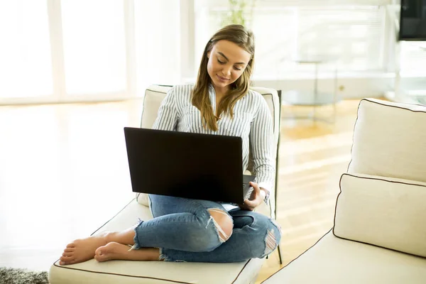 Vrouw met behulp van een laptop op de Bank in de kamer — Stockfoto