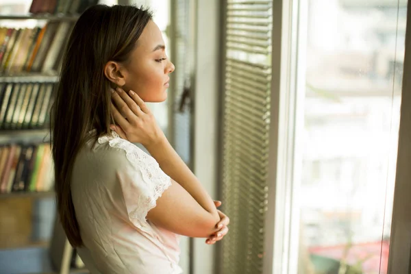 Mladá žena stojí u okna — Stock fotografie
