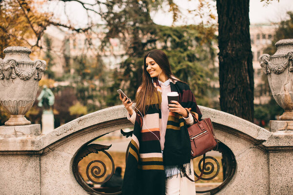 Woman with phone and coffee outdoor