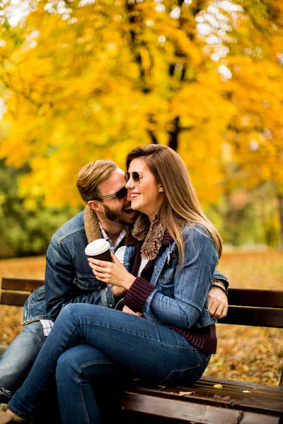 Νεαρό ζευγάρι στο Φθινοπωρινό πάρκο με καφέ — Φωτογραφία Αρχείου