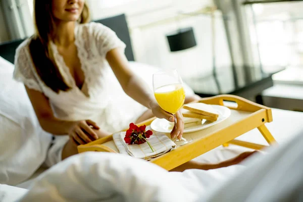 Jonge vrouw ontbijten in bed — Stockfoto