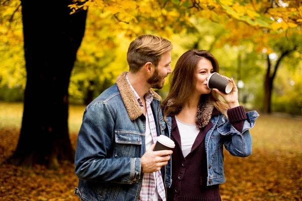 Pareja joven en el parque de otoño con café — Foto de Stock