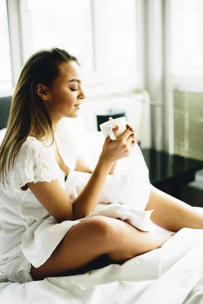 Nő ült egy ágyon, kávé — Stock Fotó