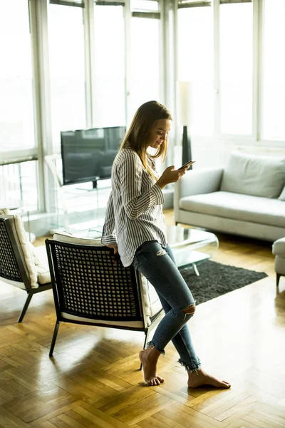 Womanin la sala de estar con teléfono móvil —  Fotos de Stock