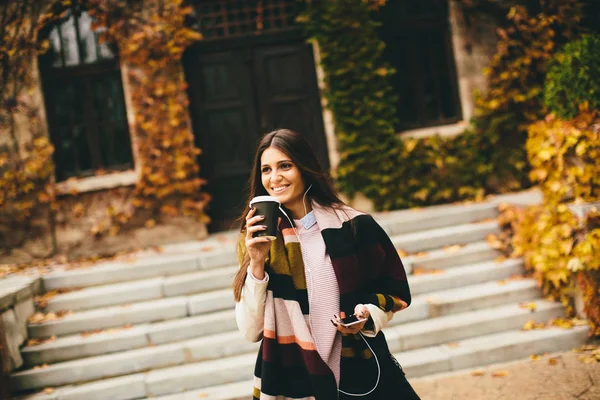 Женщина с телефоном и кофе на открытом воздухе — стоковое фото