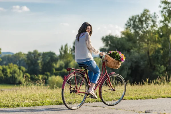 Young smiling woman rides a bicycle — Stock Photo, Image