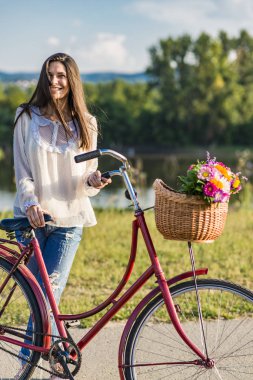 Genç gülümseyen kadın bir bisiklet ile gidiyor