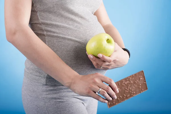 Pregnant woman with apple and chocolate — Stock Photo, Image