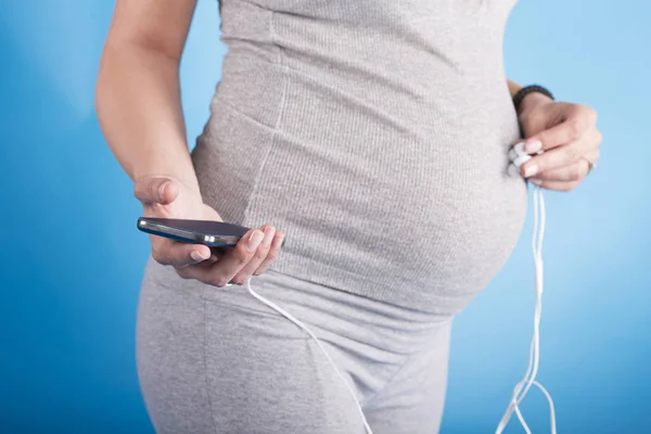 Portrait of pregnant woman putting headphones on her belly — Stock Photo, Image