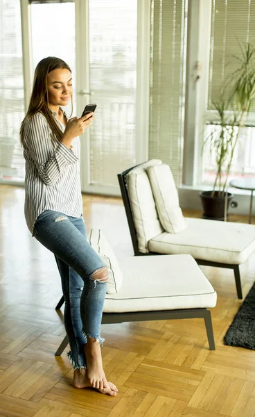 Giovane donna con telefono in camera — Foto Stock