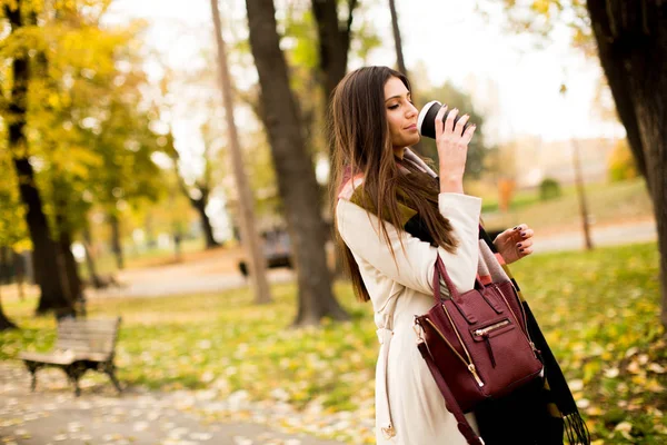 秋の公園でコーヒーを飲みながら若い女性 — ストック写真