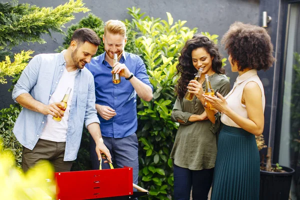 View at happy friends grilling food and enjoying barbecue party outdoors