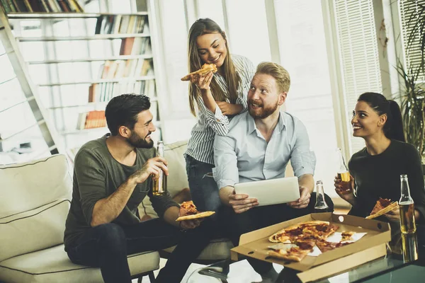 Друзья едят пиццу в современном интерьере — стоковое фото