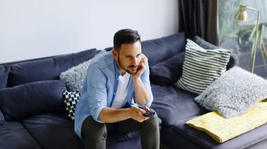 genç adam kanepede uzaktan kumanda ile