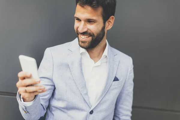 Retrato de um empresário pensativo segurando smartphone ao ar livre — Fotografia de Stock