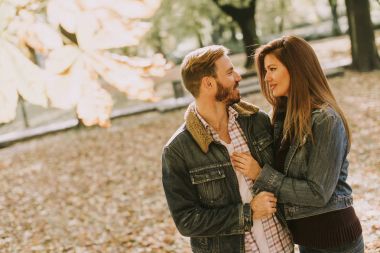 Sonbahar parkında kucaklaşan gülümseyen çift.