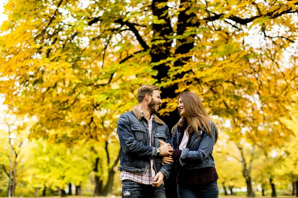 Улыбающаяся пара обнимается в осеннем парке — стоковое фото