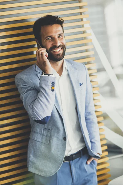 Bello giovane uomo d'affari utilizzando il telefono in ufficio — Foto Stock