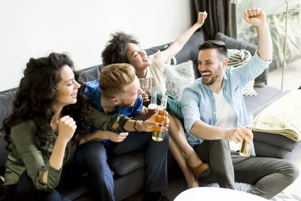 Amigos assistindo TV, bebendo cidra e se divertindo no quarto — Fotografia de Stock