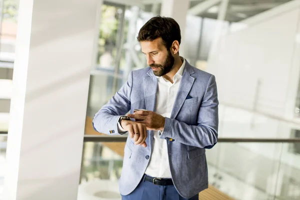 Hombre de negocios joven guapo está mirando su reloj — Foto de Stock