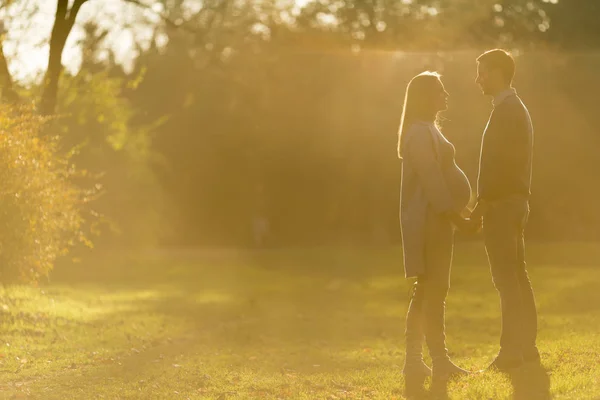 Mulher grávida e seu homem amoroso posando no parque de outono — Fotografia de Stock