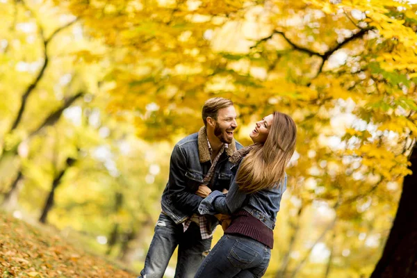 Couple souriant étreignant dans le parc d'automne et s'amusant — Photo